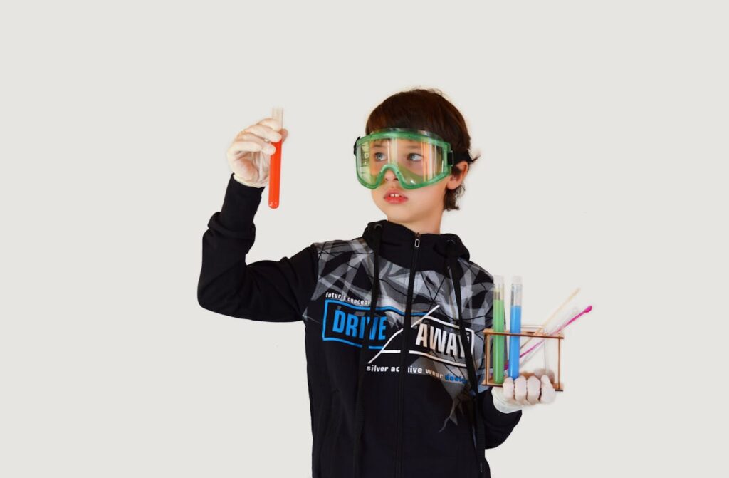 Young male scientist in protective glasses and sterile gloves with colorful liquids in transparent tubes